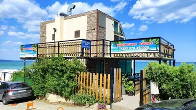 a building with a fence in front of the ocean at Hemingway rooms in Happy Beach in Varna City