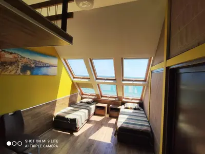 an attic room with two beds and windows at Hemingway rooms in Happy Beach in Varna City