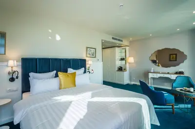 a hotel room with a large bed and chairs at Hotel Residence Promenade in Burgas City