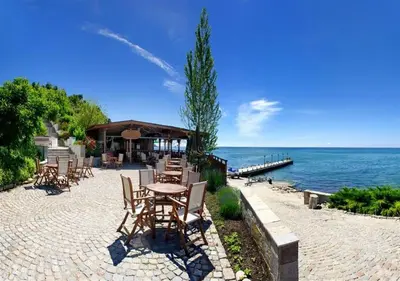 a patio with tables and chairs next to the water at ДриймБг Апартаменти - Райска Градина, Свети Влас in Sveti Vlas