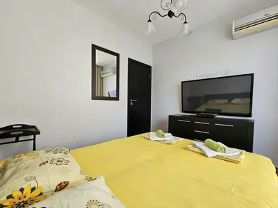 a bedroom with a yellow bed and a flat screen tv at Aпартаменти Хоризонт in Sozopol