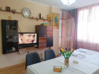 a dining room with a table and a tv on the wall at Apartament ,,EDELVAIS- LUX'' in Nesebar