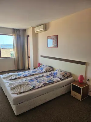 a bedroom with a bed with a night stand and a window at Hotel Orchidea in Sozopol