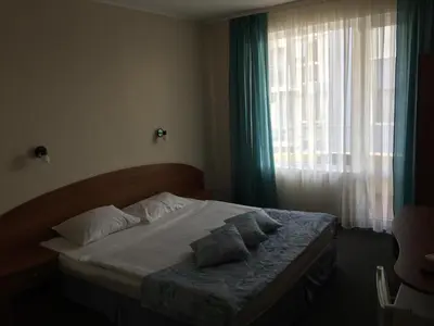 a bedroom with a bed and a window with curtains at Family Hotel Lazuren Briag in Burgas City