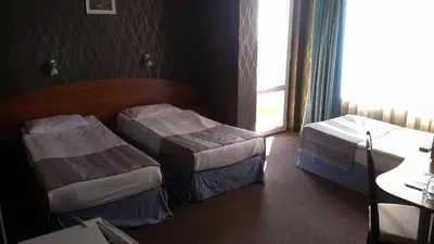 a hotel room with two beds and a window at Family Hotel Lazuren Briag in Burgas City