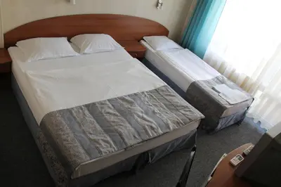 two twin beds in a room with a window at Family Hotel Lazuren Briag in Burgas City