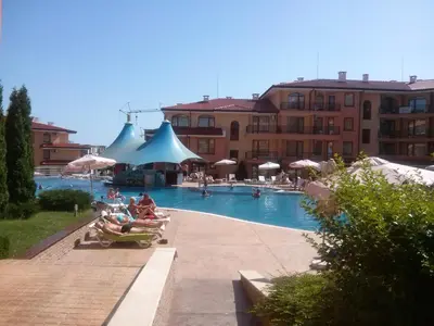 a swimming pool with people sitting in chairs next to a building at Apartcomplex Panorama Dreams in Sveti Vlas