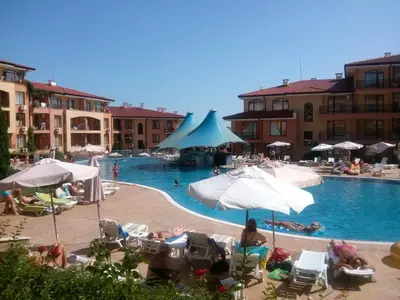 a swimming pool with people sitting in chairs and umbrellas at Apartcomplex Panorama Dreams in Sveti Vlas