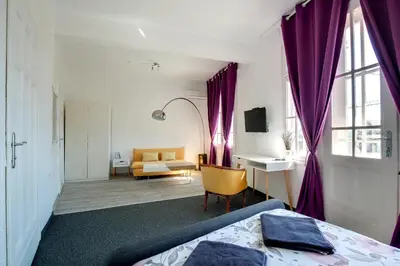 a bedroom with purple curtains and a bed and a desk at Hostel Musala in Varna City