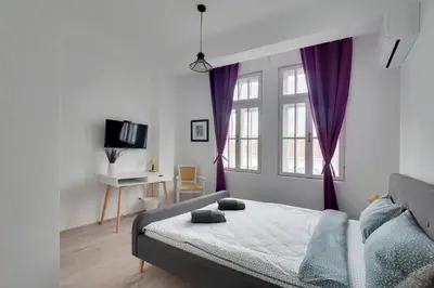 a bedroom with a bed and a window with purple curtains at Hostel Musala in Varna City