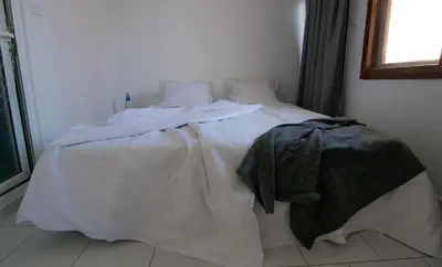 a bed with white sheets and a blanket on it at Cherry Garden Apartments in Sveti Vlas