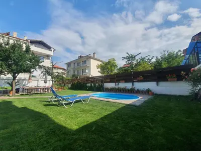 a yard with a chair and a swimming pool at Cherry Garden Apartments in Sveti Vlas