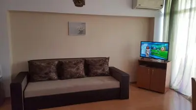 a couch in a living room with a flat screen tv at Grand Kameliq in Sunny Beach