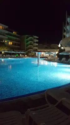 a large swimming pool with blue water at night at Grand Kameliq in Sunny Beach
