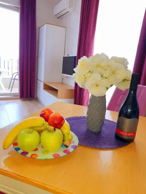 a table with a plate of fruit and a vase of flowers at Old Sailor Apartment in Obzor
