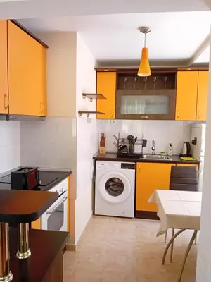 a kitchen with yellow cabinets and a washing machine at Laura in Primorsko