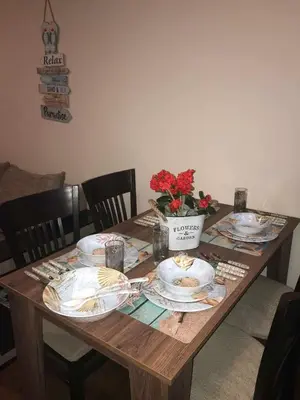 a wooden table with plates and a vase of flowers at DIAMOND APARTMENT №1 - RELAX HOLIDAY VIEWS SEA AND POOL in Burgas City