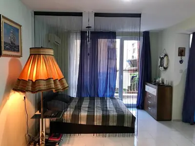 a bedroom with a bed and a lamp and a window at Alice Apartment in Obzor