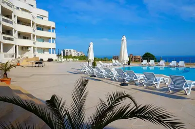 a pool with chairs and umbrellas next to a building at Апартаменти Сънбрийз - Sunbreeze Apartments in Byala