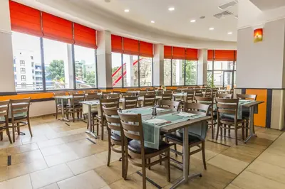 a dining room with tables and chairs and windows at Kuban Resort & Aquapark - All Inclusive in Sunny Beach