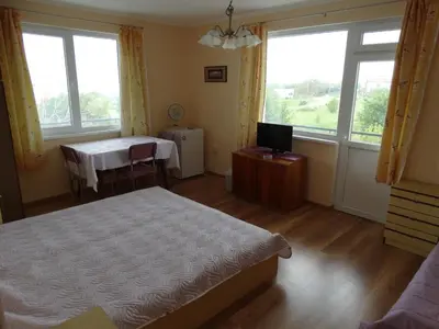 a bedroom with a bed and a table and windows at Дом Христови in Chernomorets