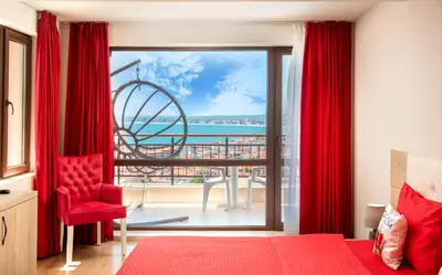 a bedroom with a red bed and a view of the ocean at Sea View Hills in Sveti Vlas
