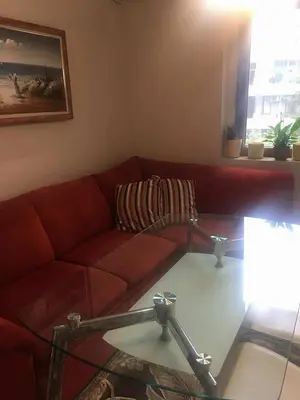 a living room with a red couch and a glass table at Apartament Peyo Yavorov in Burgas City