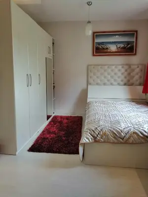 a bedroom with a bed and a red rug at Apartament Peyo Yavorov in Burgas City