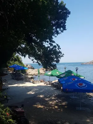 a beach with umbrellas and chairs and the water at Apartment Zora in Sozopol