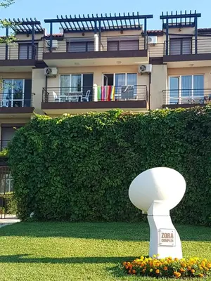 a white sculpture in the grass in front of a building at Apartment Zora in Sozopol