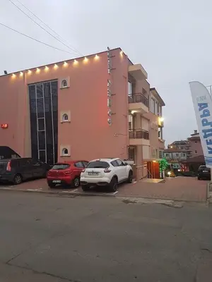 two cars parked in a parking lot in front of a building at Family Hotel Kedara in Burgas City