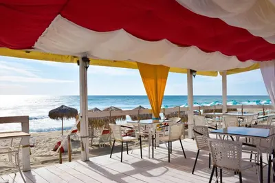 a restaurant on the beach with tables and chairs at Helga Apartment in Obzor