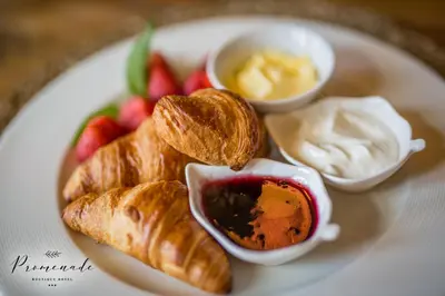 a plate of food with croissants and fruit and dip at Villa Promenade in Burgas City