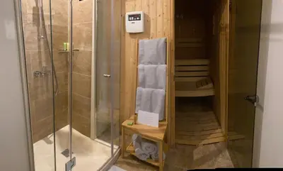 a bathroom with a shower and towels on a shelf at Villa Promenade in Burgas City