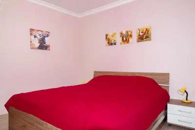 a bedroom with a red bed and three pictures on the wall at Apartment EliMar in Burgas City