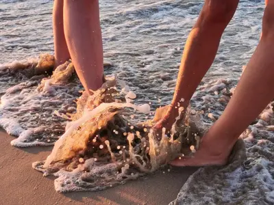 two people standing in the sand on the beach at Apartment EliMar in Burgas City