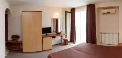 a bedroom with a bed and a desk with a television at Guest House Ianis Paradise in Nesebar