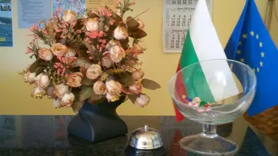 a vase with a bouquet of flowers next to a trophy at Hotel Blian in Ravda