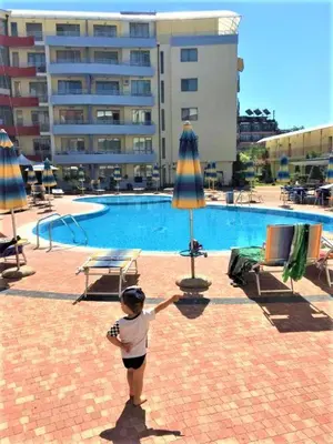a young child standing in front of a swimming pool at Central Plaza Apartment in Sunny Beach