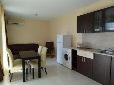 a kitchen with a table and a kitchen with a refrigerator at Triumph Holiday Village in Sveti Vlas