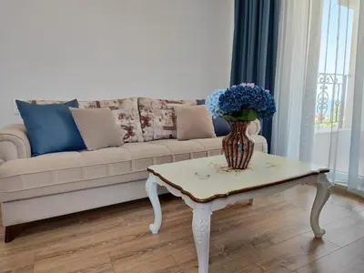 a living room with a couch and a vase of flowers on a table at Apartment RAYA in Obzor