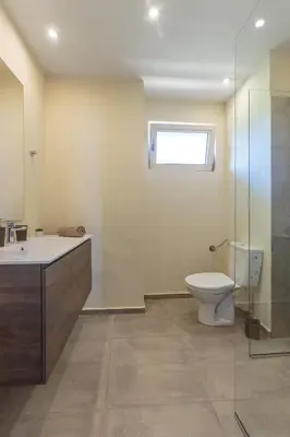 a bathroom with a toilet and a sink and a window at Coral Luxury Villas in Lozenets