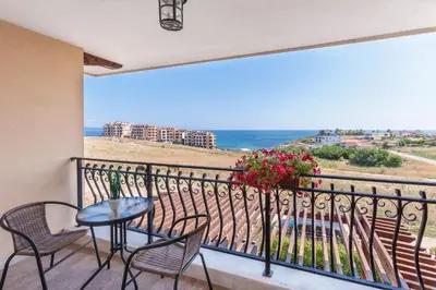 a balcony with a table and chairs and a view of the ocean at Coral Luxury Villas in Lozenets