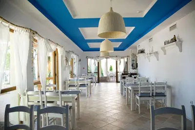 a restaurant with blue ceilings and white tables and chairs at Bay Apartments Sozopol in Sozopol