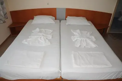 two beds in a room with white sheets and towels at Hotel Babeva in Sveti Vlas