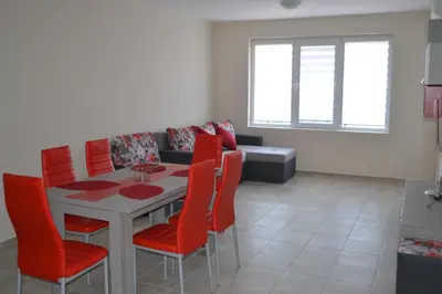 a dining room with a table and red chairs at Апартаменти Кастро/Castro Apartments in Tsarevo