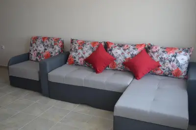 a couch with two red pillows on it at Апартаменти Кастро/Castro Apartments in Tsarevo