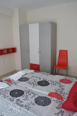 a bedroom with a bed and a red chair at Апартаменти Кастро/Castro Apartments in Tsarevo
