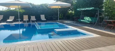 a swimming pool with chairs and tables and an umbrella at Iva Resort in Byala
