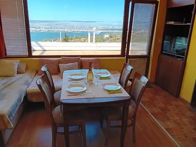 a dining room with a table and chairs and a window at Apartament Zaliva in Varna City
